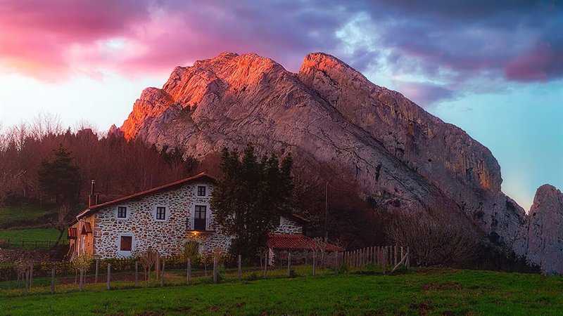 Casa rural a los pies de una montaña al atardecer